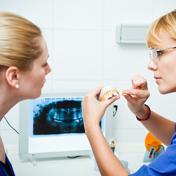 lady dantist showing dental implant to the patient